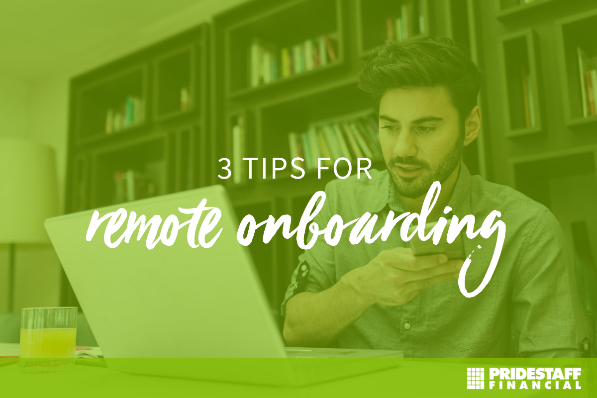 Hispanic man with long dark brown hair and a beard is looking at his laptop. He has his phone in hand. Behind him, there is a library of books in tall shelves that go from the floor to ceiling..